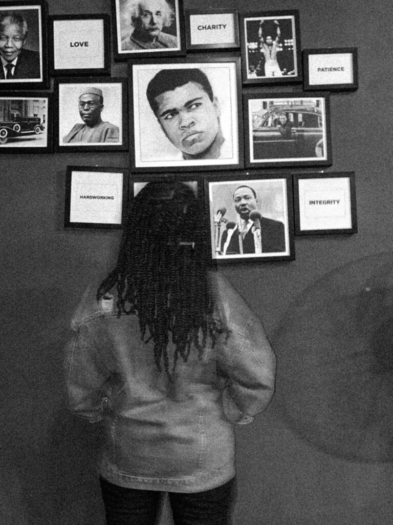 A black woman staring at iconic pictures on the wall.